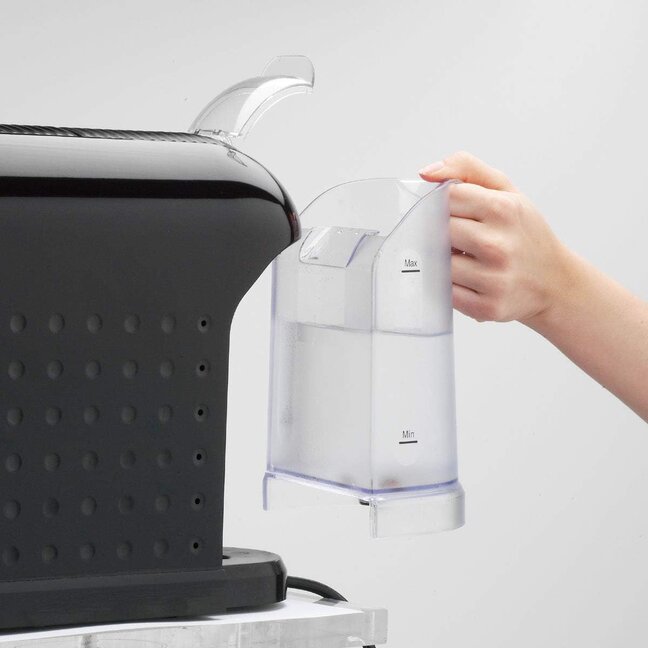 Une personne remplit le réservoir d'eau d'une élégante machine à café à capsules noire, assurant ainsi une infusion parfaite.