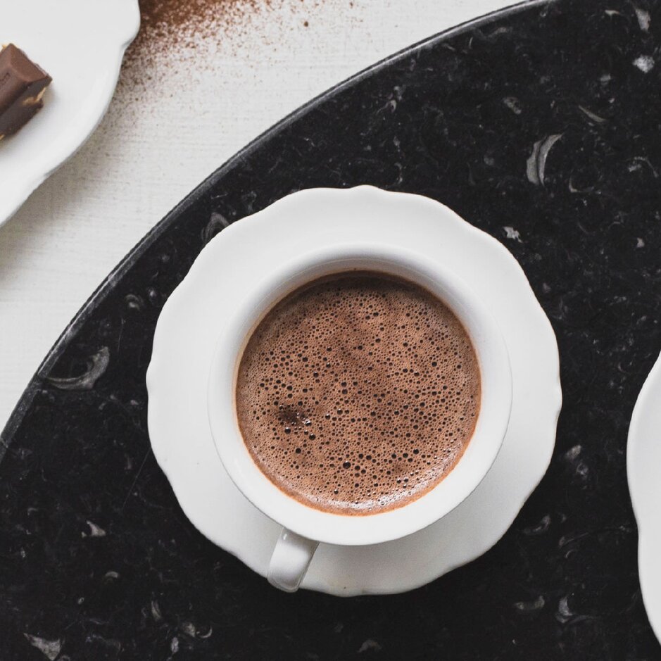 Reichhaltige heiße Schokolade, serviert mit Schokoladenquadraten und Milch, perfekt für einen köstlichen Genuss.