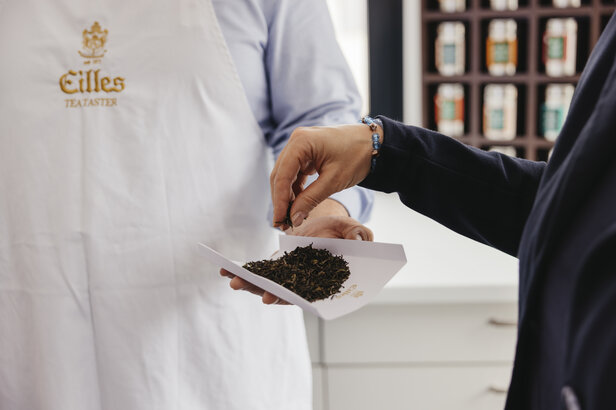 Degustator herbaty bada liście zielonej herbaty, prezentując sztukę degustacji herbaty w wyrafinowanym otoczeniu.