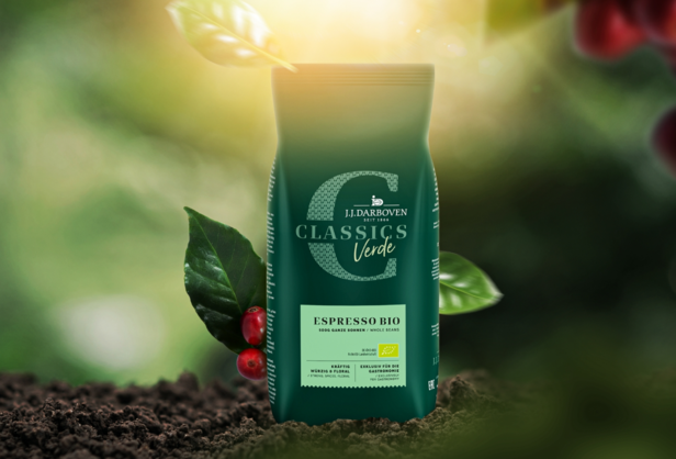 Vrecko na organickú kávu espresso od spoločnosti J.J. Darboven so žiarivo zeleným dizajnom a kávovými zrnami na prírodnom pozadí.