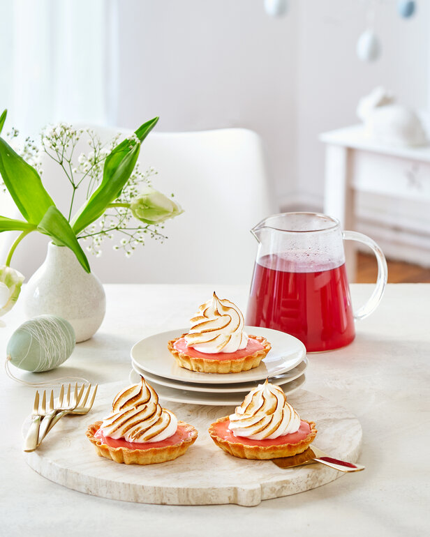 Vynikajúce citrónové koláče s pusinkami, podávané s kvetinovou výzdobou a džbánom ružového nápoja, ideálne na popoludňajší čaj.