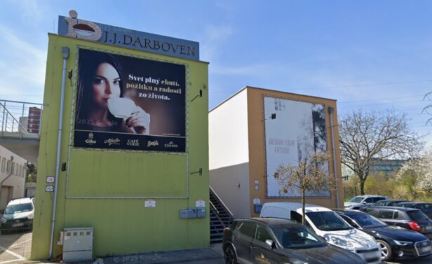 Na budove spoločnosti J.J. Darboven sa nachádza žiarivá reklama, ktorá upozorňuje na ponuku kávy a dizajnový slogan.