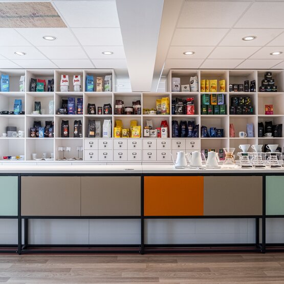 Modernes Coffeeshop-Interieur mit einer bunten Auslage von Tee- und Kaffeeprodukten in stilvollen Regalen.