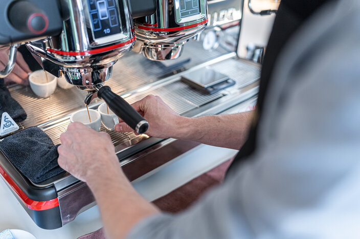 A barista expertly prepares espresso using a professional coffee machine, showcasing skilled coffee-making techniques.