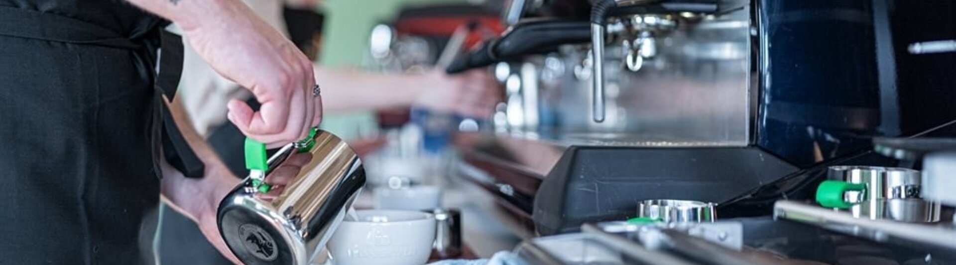 Barista-trainingssessie met personeel dat espressomachines en melkopschuimers gebruikt om koffiedranken te maken.