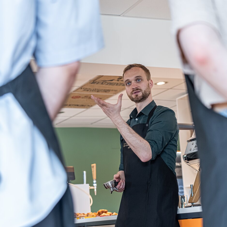 Der Barista lehrt in einer Schulung in einem modernen Café die Techniken der Kaffeezubereitung und unterstreicht dabei seine Fähigkeiten und Kenntnisse.