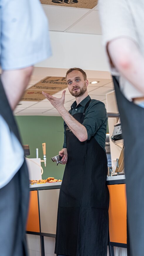 Der Barista lehrt in einer Schulung in einem modernen Café die Techniken der Kaffeezubereitung und unterstreicht dabei seine Fähigkeiten und Kenntnisse.