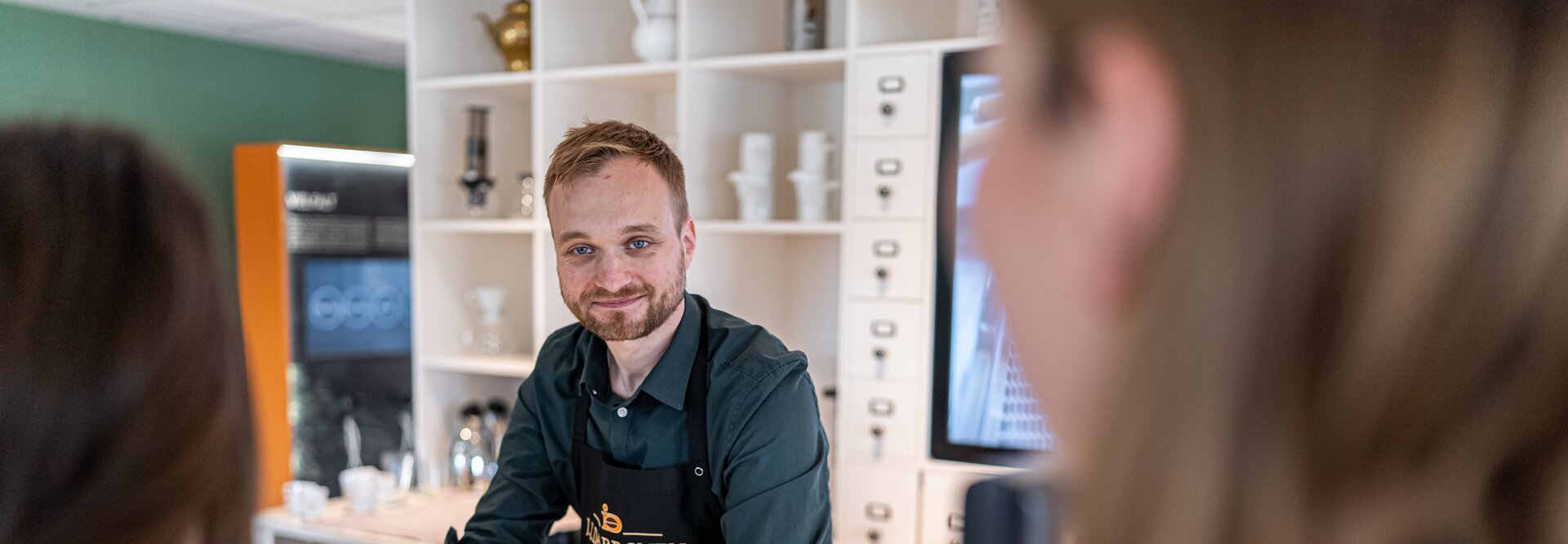 Barista serveert koffie in een stijlvol café en creëert een gastvrije sfeer voor klanten in een moderne omgeving.