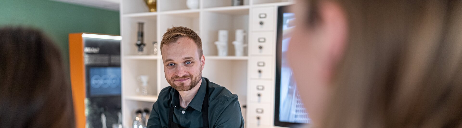 Barista serveert koffie in een stijlvol café en creëert een gastvrije sfeer voor klanten in een moderne omgeving.