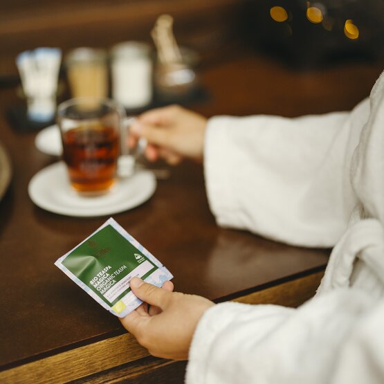 Enjoying organic tea in a robe, with a beverage on a wooden table and sugar options in the background.