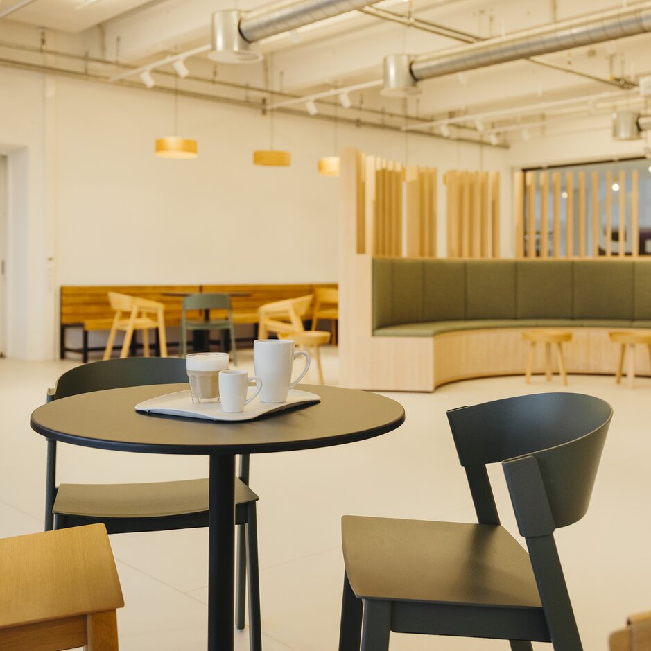 Modern café interior with minimalist seating, a round table set for coffee, and warm wooden accents creating a welcoming atmosphere.