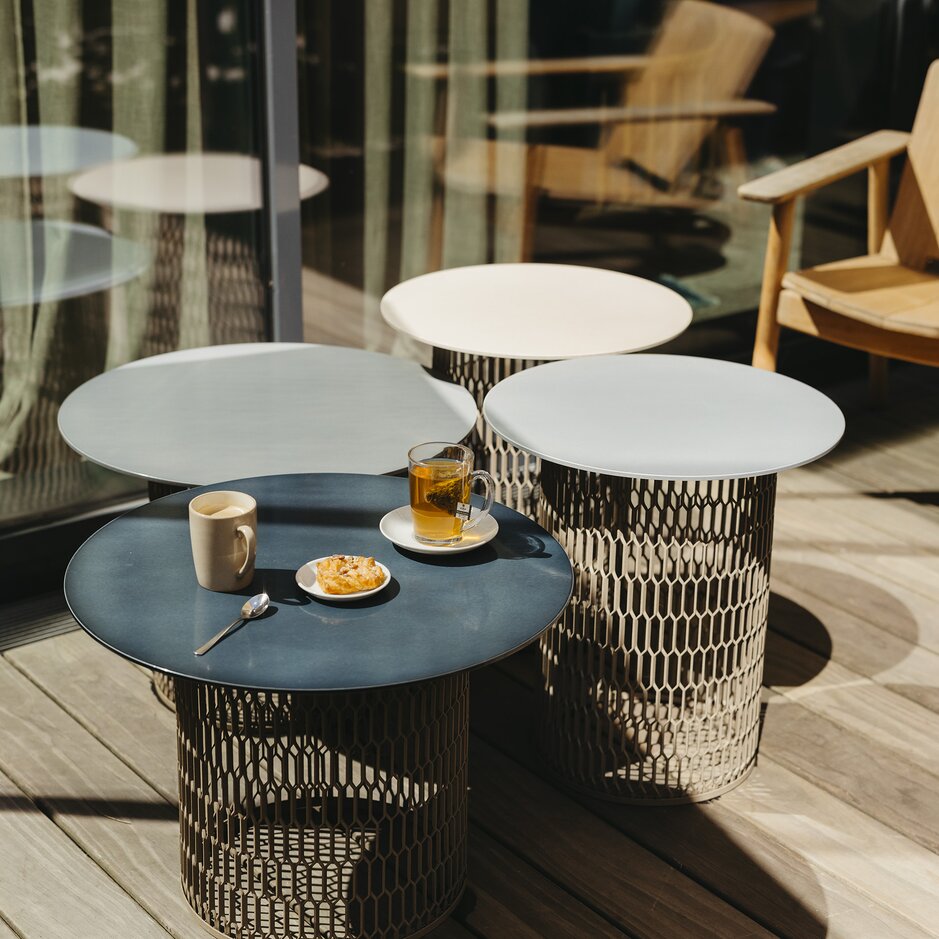 Stilvolle Sitzgelegenheiten im Freien mit Kaffee, Tee und Gebäck auf modernen Tischen, ideal zum Entspannen in der Sonne.