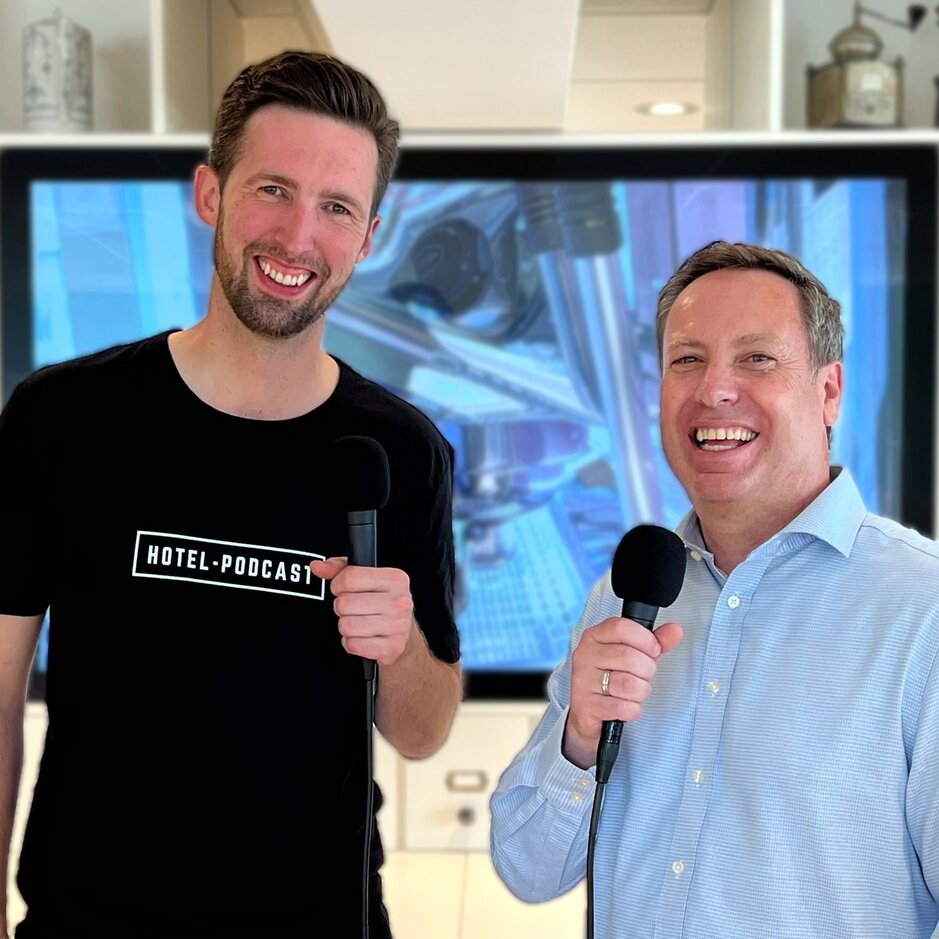 Martin and Ronald pose with microphones, promoting their engaging hotel podcast in a stylish setting.