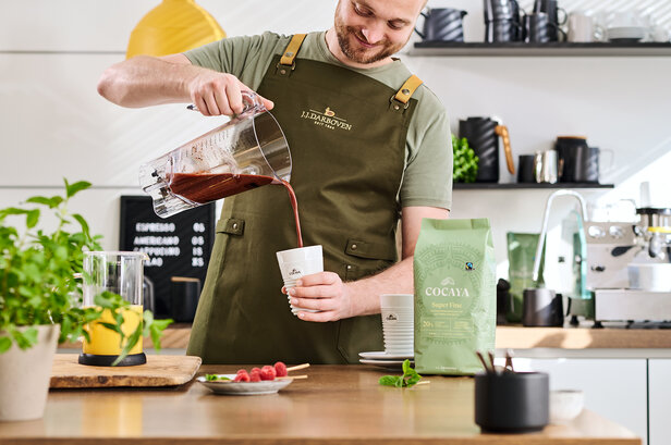 Ein köstlicher Himbeer-Smoothie wird in eine Tasse gegossen, wobei die Zutaten von Cocaya Super Fine in einer modernen Küche präsentiert werden.