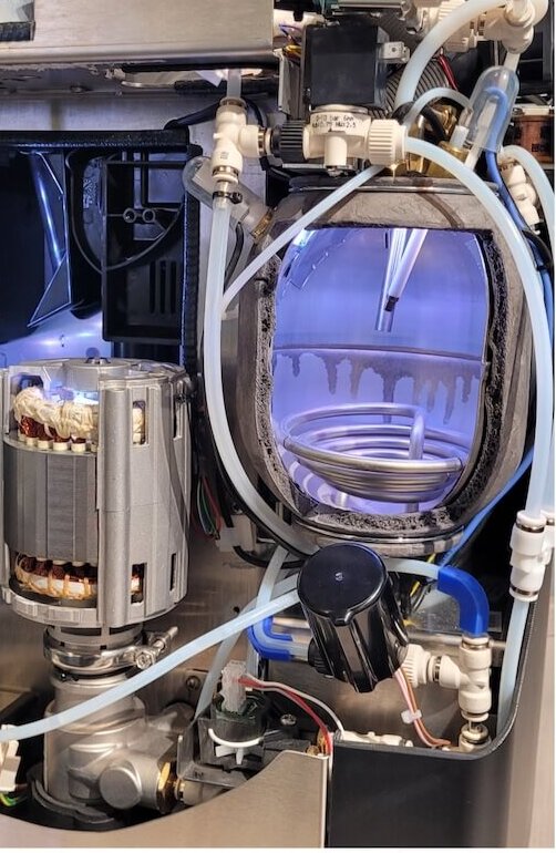 Interior view of a coffee machine showcasing its pump, tubing, and components for optimal brewing.