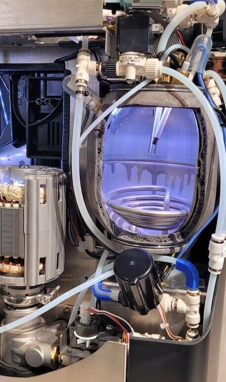 Interior view of a coffee machine showcasing its pump, tubing, and components for optimal brewing.