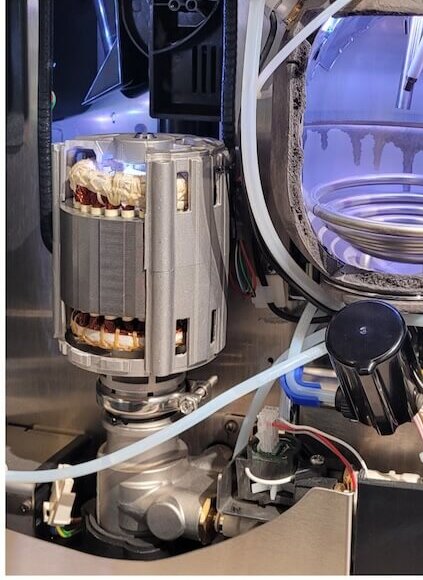 Interior view of a coffee machine showcasing its pump, tubing, and components for optimal brewing.