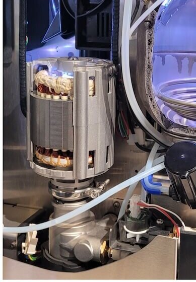 Interior view of a coffee machine showcasing its pump, tubing, and components for optimal brewing.