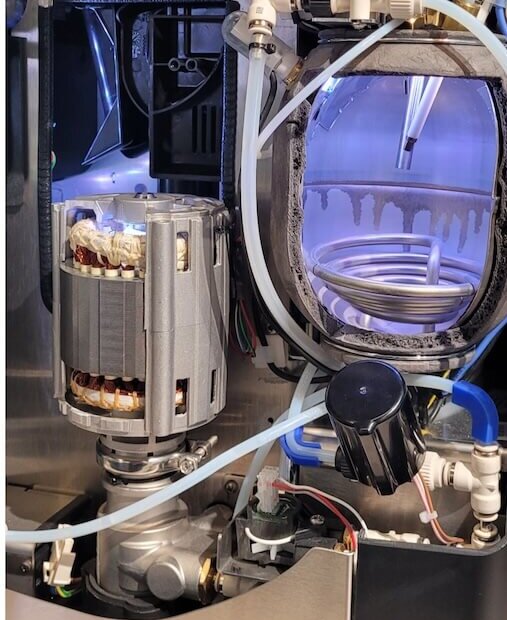 Innenansicht einer Kaffeemaschine, die die Pumpe, die Schläuche und die Komponenten für eine optimale Zubereitung zeigt.