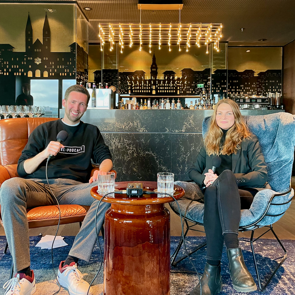 Podcast hosts recording in a stylish setting, discussing engaging topics with drinks on a coffee table.