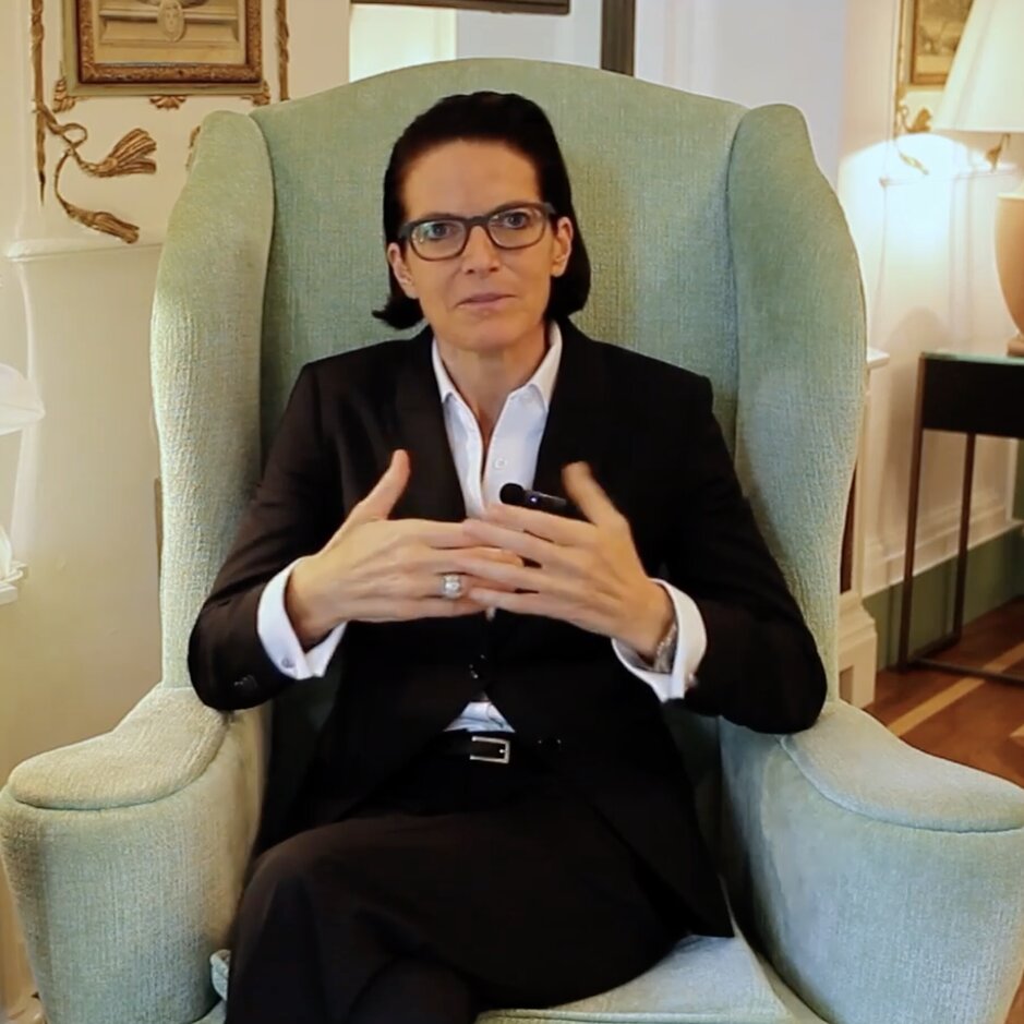 Berufstätige Frau im Anzug sitzt in einem eleganten Sessel und bespricht Themen in einem eleganten Interieur.