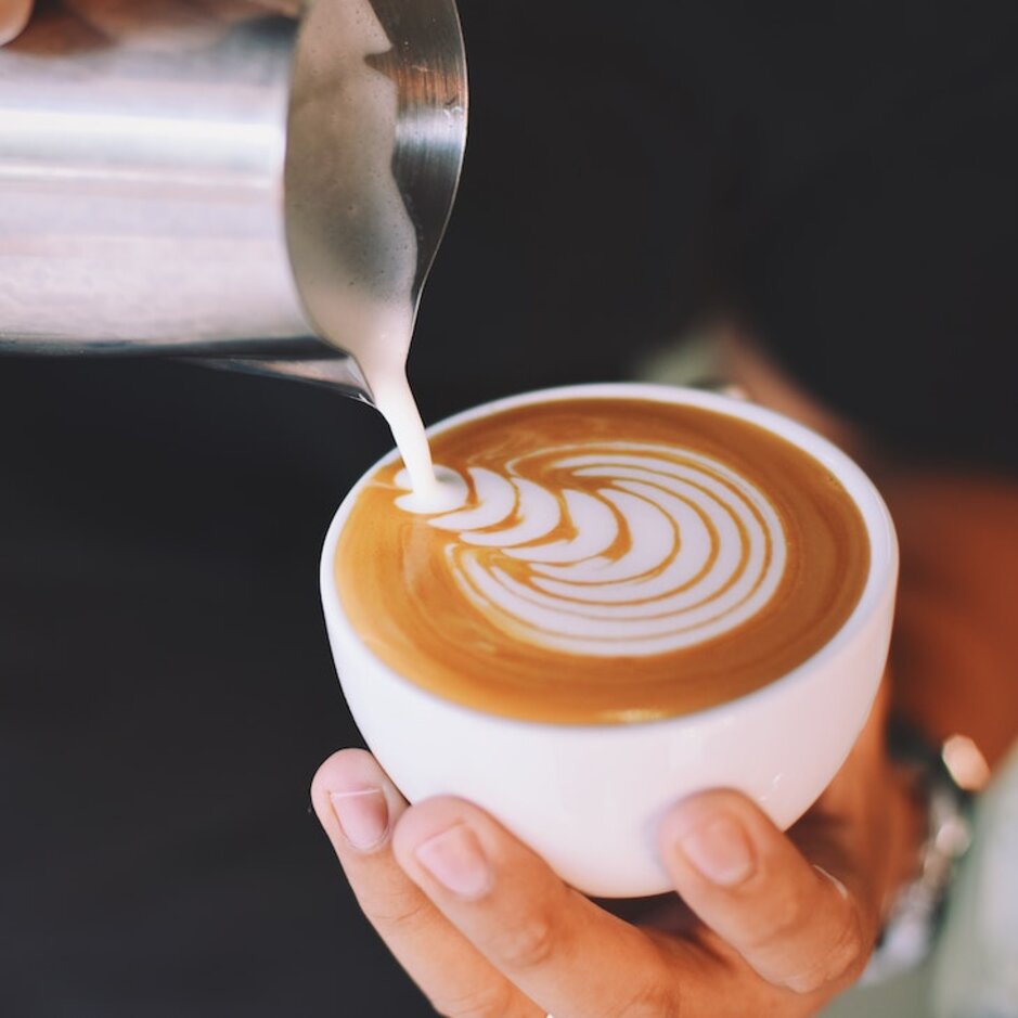 Perfectly poured milk foam creates a stunning latte art design in a white cup, showcasing barista skills.