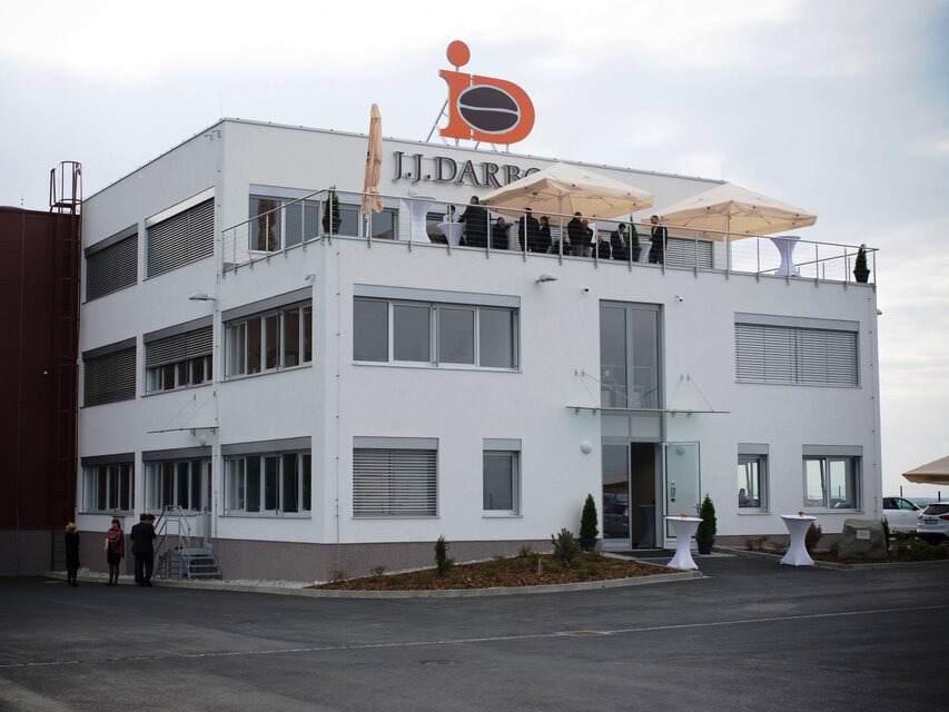 Modern J.J. Darboven building with a rooftop terrace, hosting an outdoor event in a scenic setting.