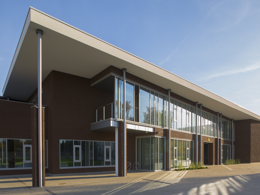 Modern headquarters featuring large glass windows and elegant architectural design set against a clear blue sky.