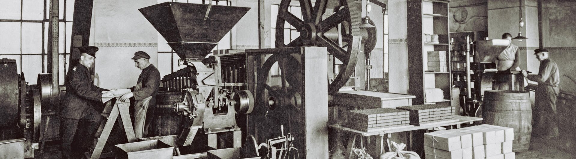 Historyczna scena produkcji kawy przedstawiająca pracowników i maszyny w zabytkowej palarni. Dziedzictwo J.J. Darboven.
