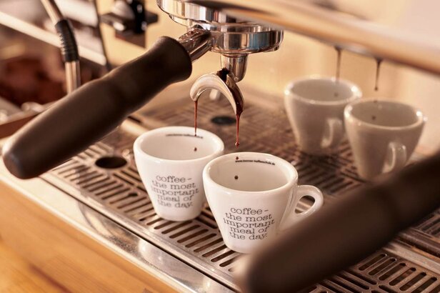 Vers gezette koffie stroomt in twee kopjes en benadrukt het belang van koffie in het dagelijks leven. Perfect voor café-enthousiastelingen.