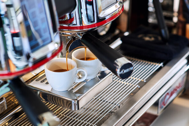 Frischer Espresso wird von einer professionellen Maschine in zwei weiße Tassen gebrüht, die die Kunst der Kaffeezubereitung zeigen.