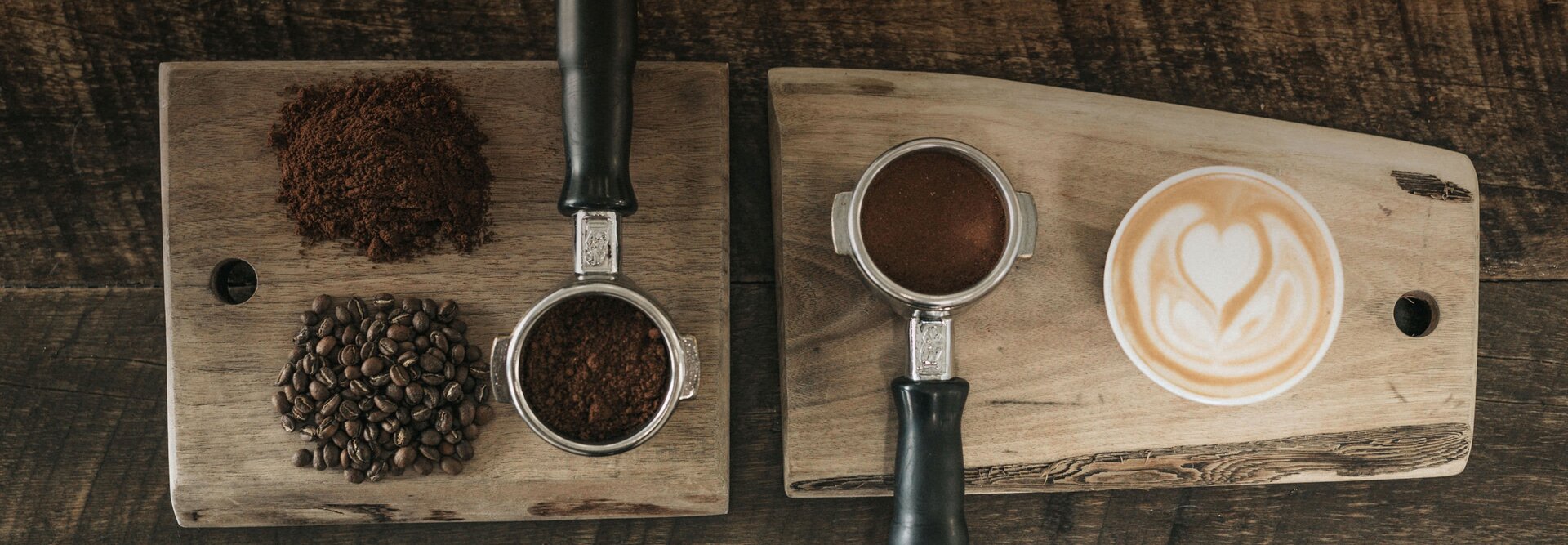 Vers gemalen koffie en bonen in combinatie met een prachtig bewerkte latte art op houten serveerplanken.