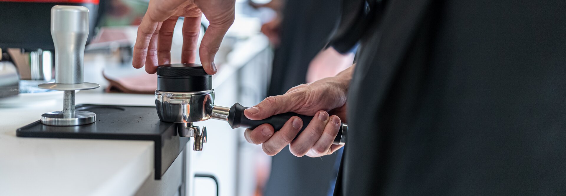 Barista preparing coffee with a portafilter at a modern café, showcasing brewing techniques at TopMood Akademie.