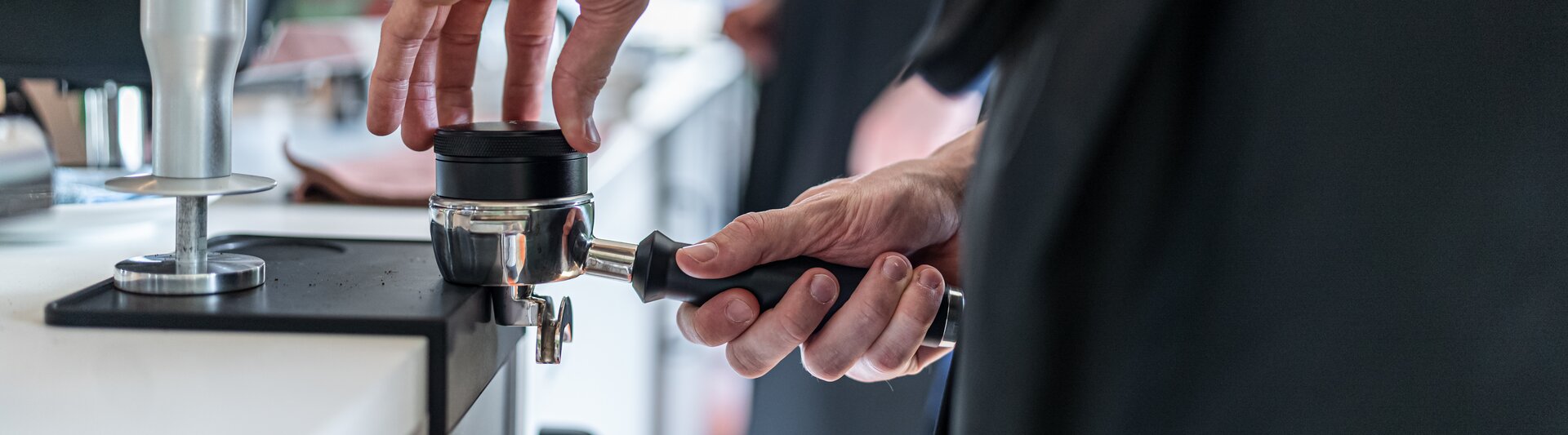 Barista préparant du café avec un portafilter dans un café moderne, présentant les techniques d'infusion à la TopMood Akademie.