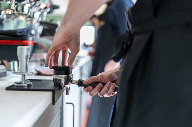 Barista bei der Zubereitung von Kaffee mit einem Portafilter in einem modernen Café, das die Brühtechniken der TopMood Akademie vorstellt.