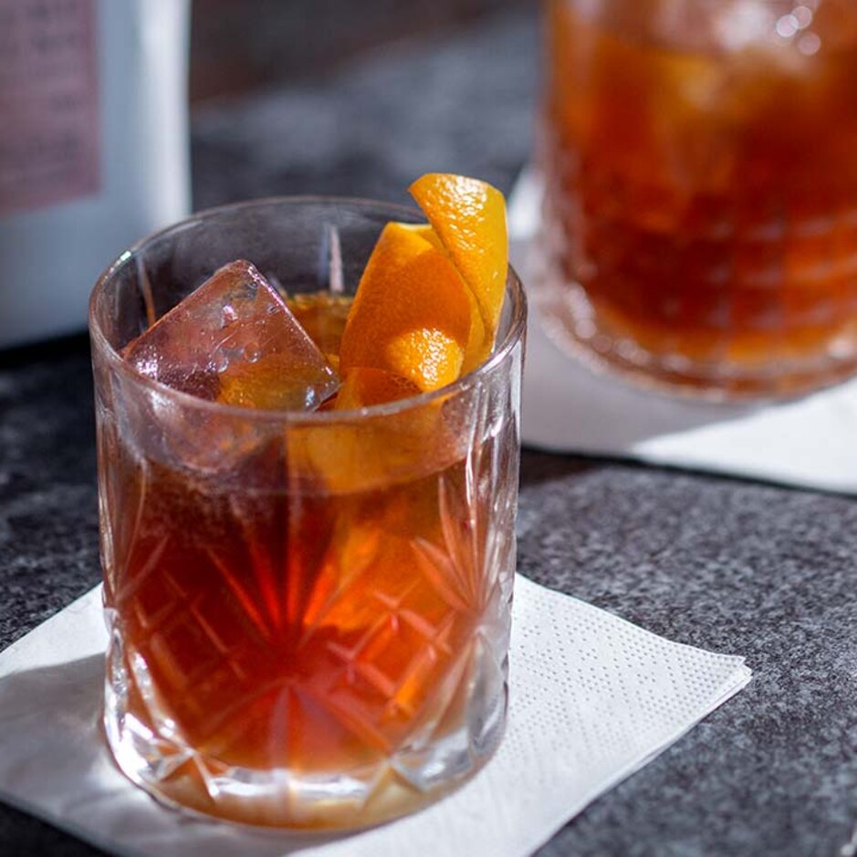 Stilvolle Cocktails auf einem Tisch, mit Orangengarnitur und Gläsern, perfekt für ein modernes Getränkekonzept.