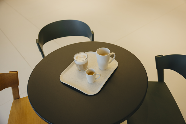 Kaffee und Milchkaffee, serviert auf einem Tablett, das auf einem schwarzen Tisch in einer modernen Caféumgebung steht. Perfekt für Kaffeeliebhaber.