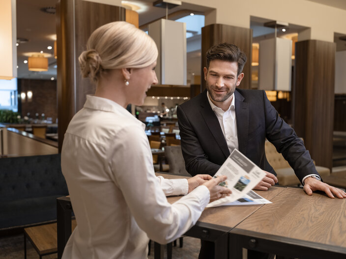 A professional man and woman discuss a menu in a stylish restaurant, showcasing a relaxed dining atmosphere.