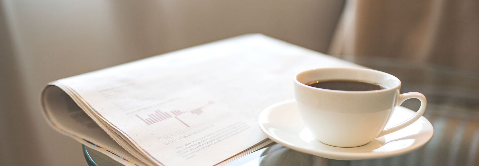 Freshly brewed coffee beside a newspaper, perfect for a morning of reading and updates on professional news.