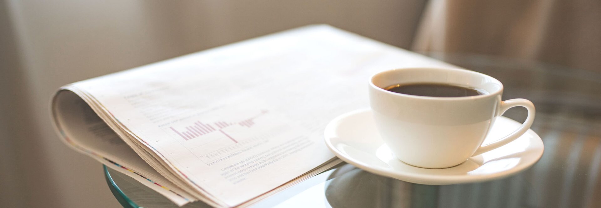 Frisch gebrühter Kaffee neben einer Zeitung, perfekt für einen Morgen voller Lektüre und aktueller beruflicher Neuigkeiten.