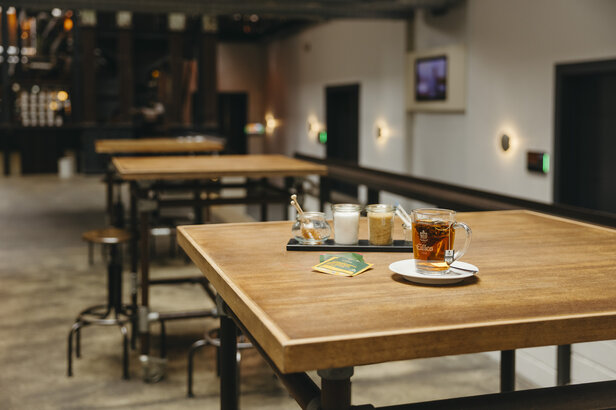 Stylowe wnętrze kawiarni z drewnianymi stołami, filiżanką herbaty i przyprawami zapewniającymi relaksującą atmosferę.