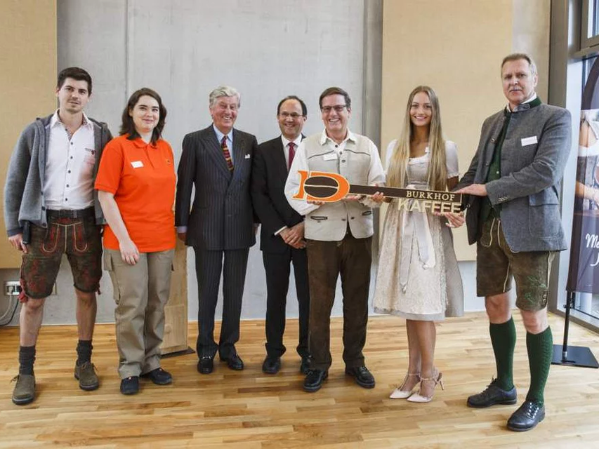 Celebrating the Burkhof coffee handover with local figures in traditional attire, highlighting Bavarian culture and community spirit.
