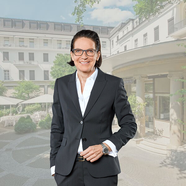 Kretschmann Hotellerie, ein Profi in eleganter Kleidung, posiert selbstbewusst vor dem Hintergrund eines Luxushotels.