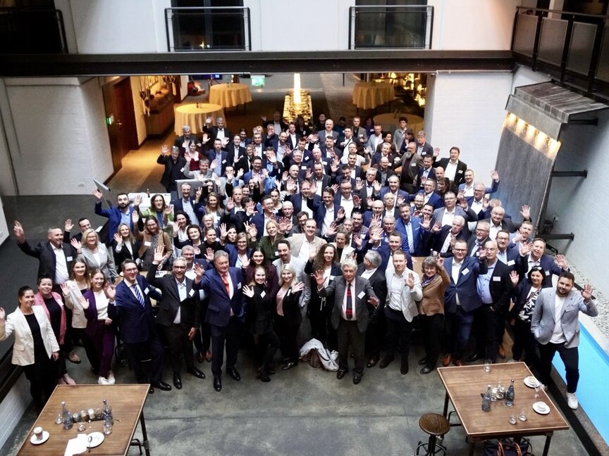 Événement de mise en réseau avec divers professionnels, saluant et souriant, dans un lieu moderne à l'atmosphère détendue.