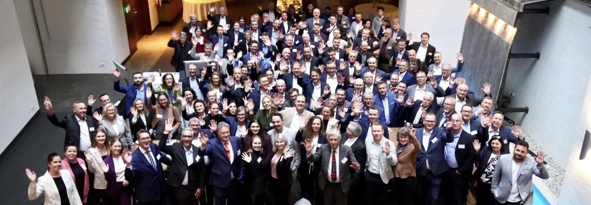 Événement de mise en réseau avec divers professionnels, saluant et souriant, dans un lieu moderne à l'atmosphère détendue.