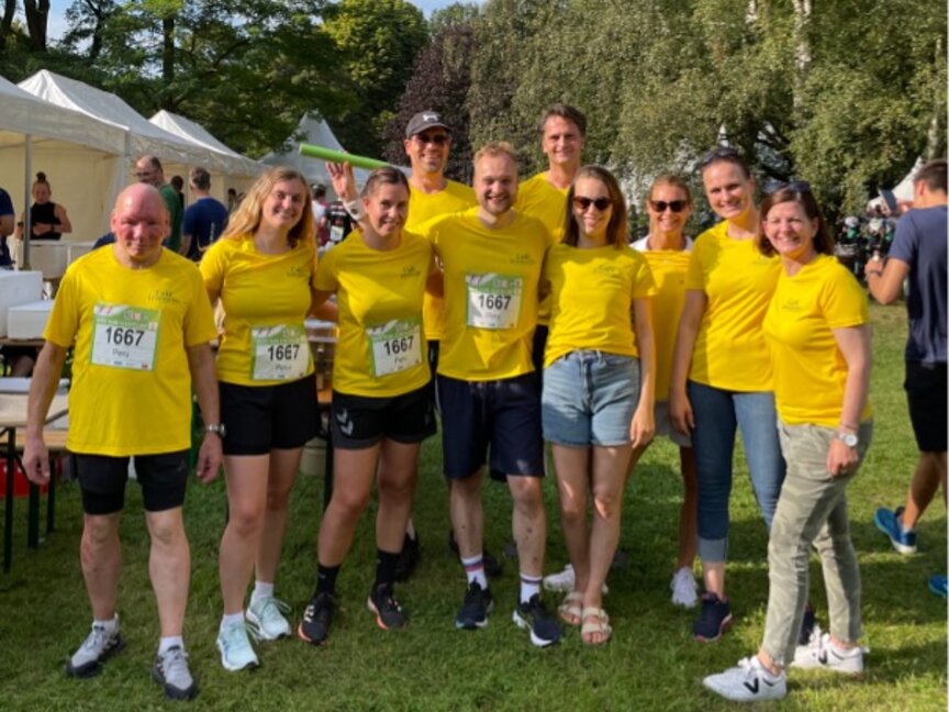 Des participants vêtus d'un maillot jaune vif posent lors d'une course à pied amusante, mettant en avant l'esprit d'équipe et la camaraderie.
