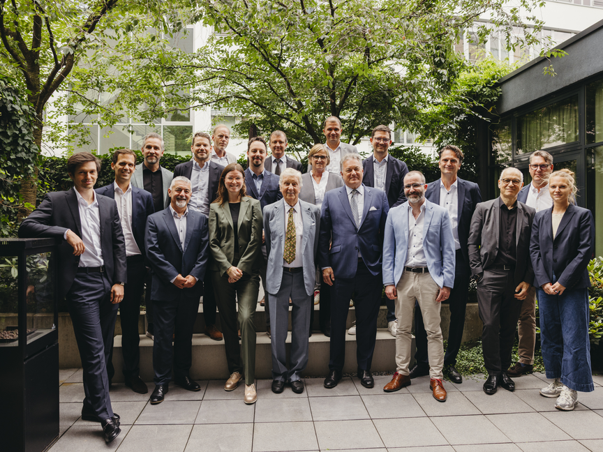 Des chefs d'entreprise se réunissent pour une photo de groupe dans un jardin urbain luxuriant, mettant en avant la collaboration et le professionnalisme.