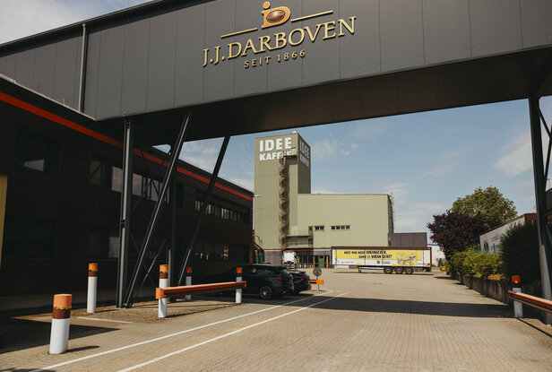 Entrance of J.J. Darboven, a coffee company, showcasing modern buildings and signage on a sunny day.