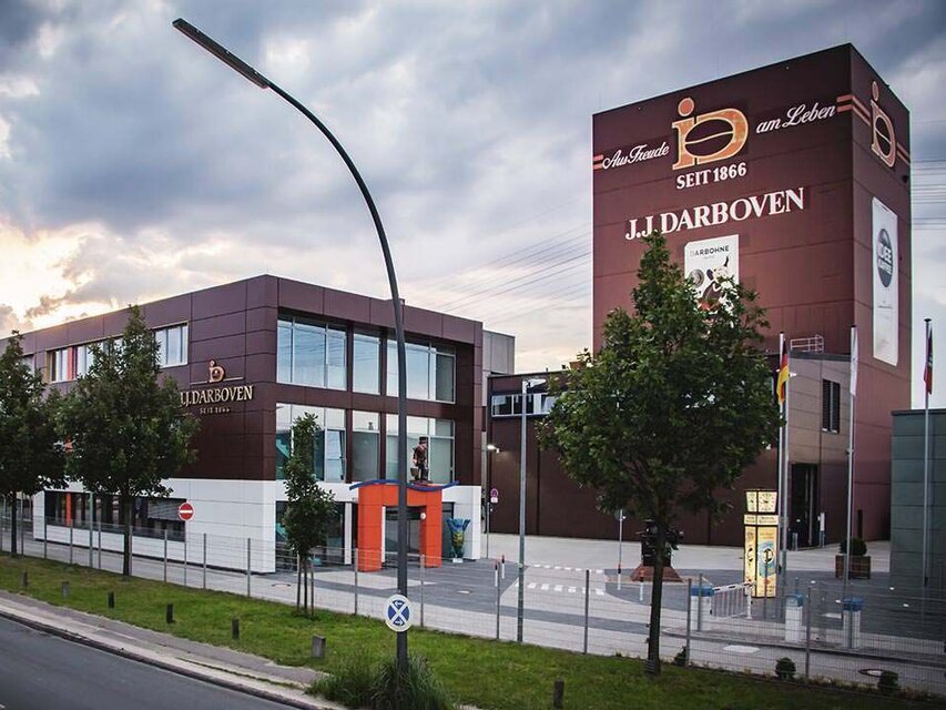 J.J. Darboven headquarters featuring modern architecture amidst trees and streetlights, showcasing the brand's history since 1866.