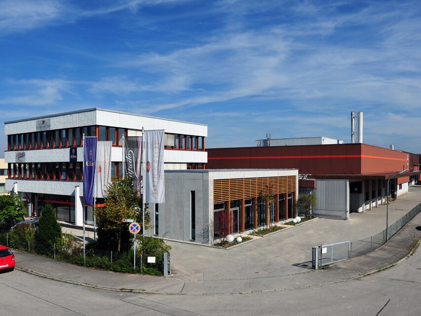 Modern industrial building in Sauerlach, featuring offices and a factory, under a clear blue sky.